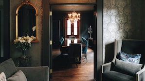 Un coin repas agrémenté d’un lustre, d’un miroir et d’une composition florale.
