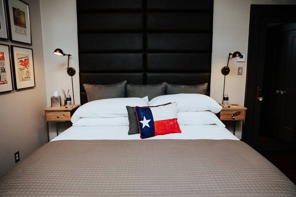 Een hotelkamer met een groot bed, twee nachtkastjes, een hoofdeinde en ingelijste foto's aan de muur.