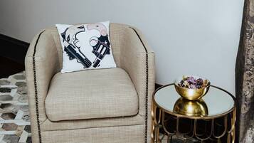 A beige sofa with a decorative pillow, a round gold side table with a bowl of flowers, and a tiled floor.