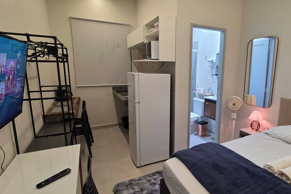 Une chambre d’hôtel comprenant un lit, un bureau avec une télévision, un réfrigérateur, un four à micro-ondes et une petite kitchenette.