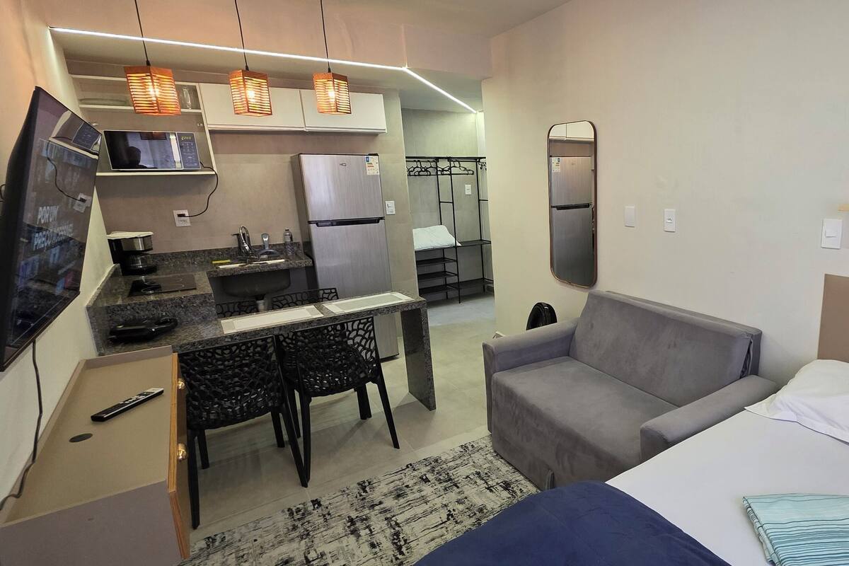 Une chambre d’hôtel compacte comprenant un coin cuisine, un lit, un canapé et une télévision.
