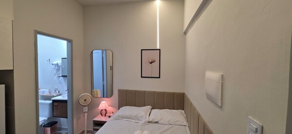 A hotel room with a bed, bedside table, lamp, mirror, and a framed picture on the wall. - Delta Acomodações (São Paulo)