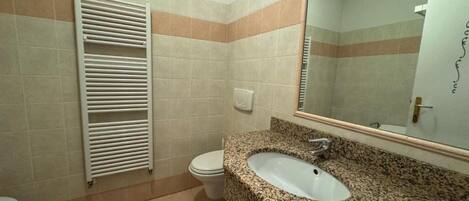 A bathroom with a granite sink, a white toilet, and a towel rack.