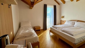 A room with two beds, wooden beams, a window with curtains, and a small bedside table. - HC HOTEL GARNI ROOM AND APARTMENT (Cembra)