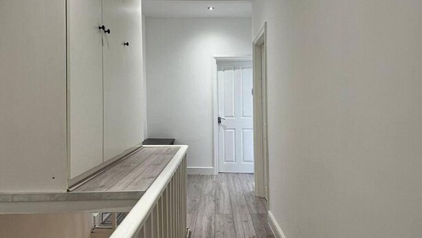 A narrow hallway with a wooden floor, white walls, and a white door at the end. - 3 bed Hackney/Harringay Flat (London)