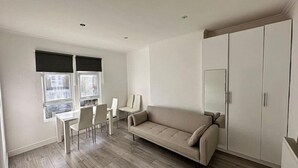 A modern living room with a sofa, chairs, a dining table, and a wardrobe. - 3 bed Hackney/Harringay Flat (London)