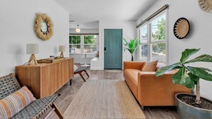 A modern living room with a wooden cabinet, a sofa, a bench, and a large potted plant. - *NEW San Diego Home-Private Hot Tub & Views+Pet (San Diego)