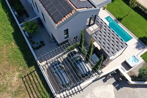 A modern building with a swimming pool, solar panels, and a fenced parking area. - Luxury Villa Casa Tia with Pool, Jacuzzi, Sauna (Porec)