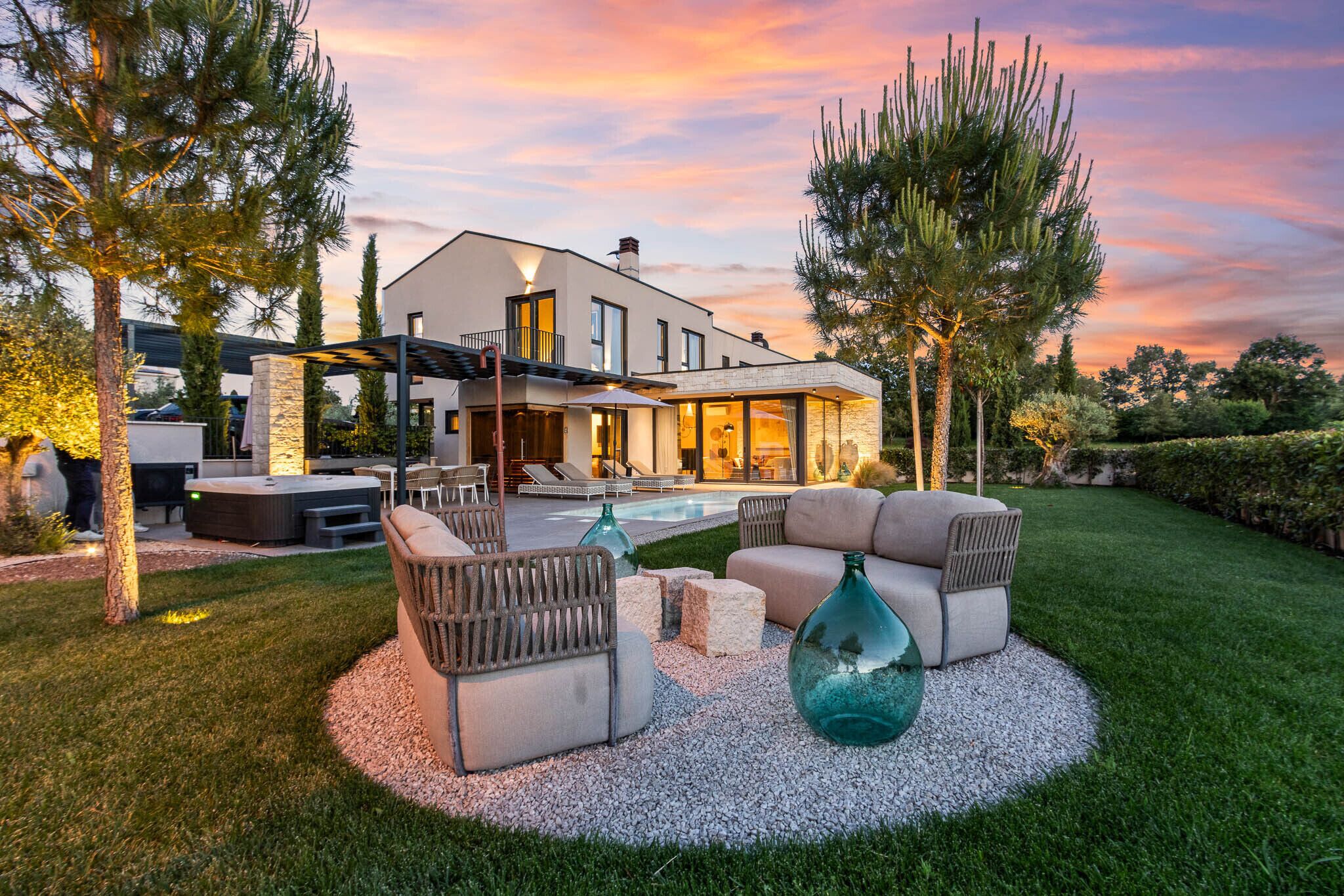 Una casa moderna con piscina, mobiliario exterior y un césped cuidado.