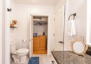 Un baño con inodoro, lavamanos, tocador y espejo.