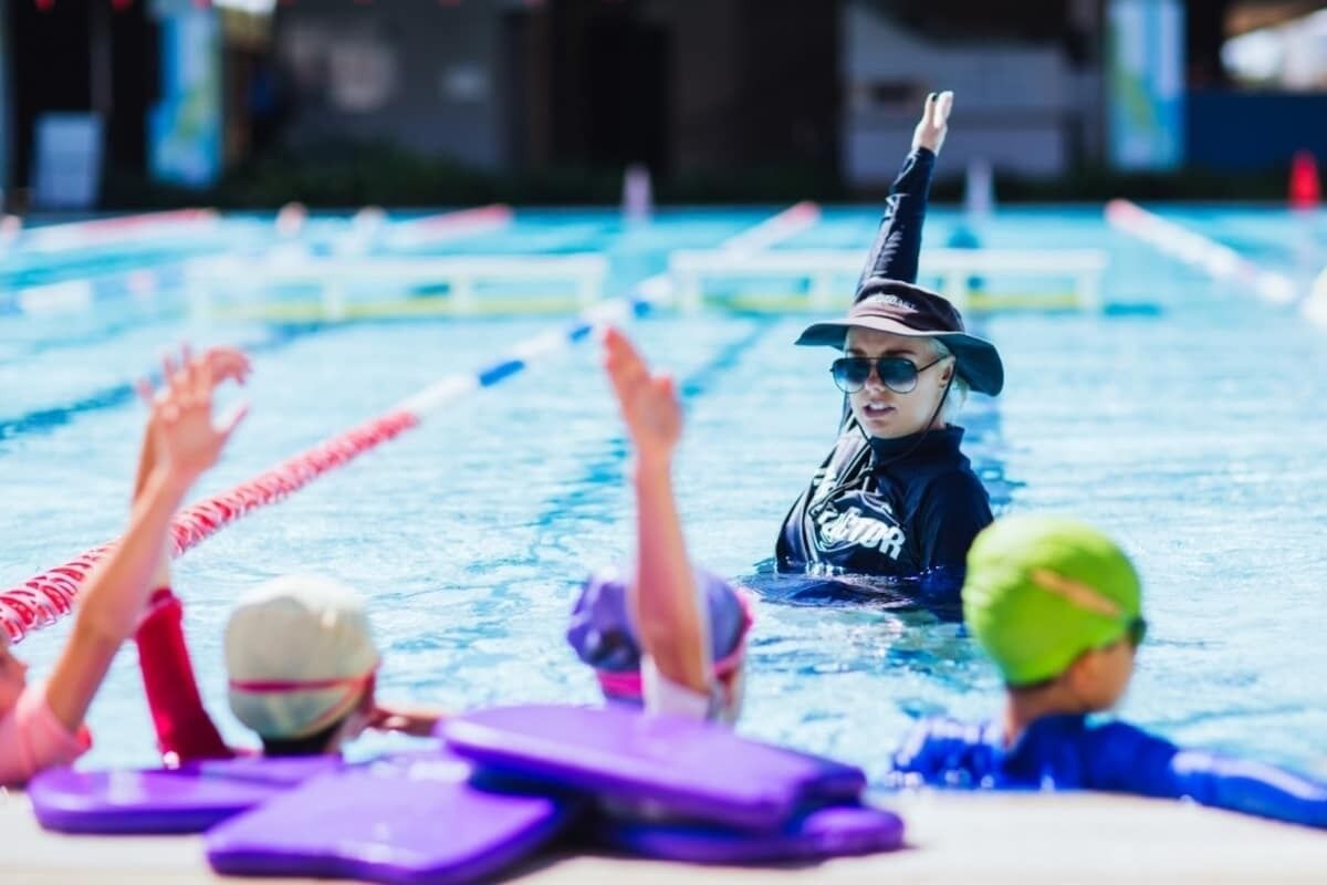 A swimming pool with lane dividers and people swimming.