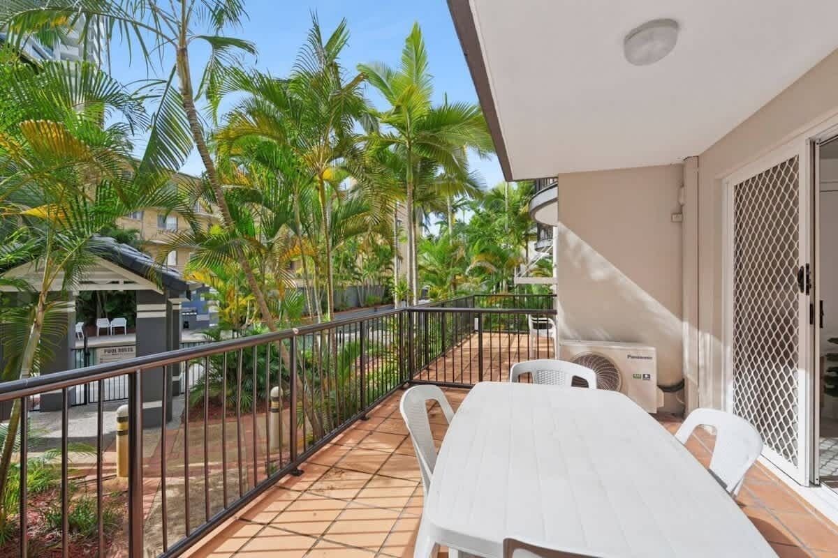 A balcony with a white table and chairs, surrounded by a metal railing.