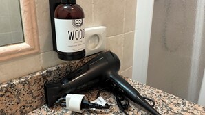 Ein Badezimmer mit Fön, einer Seifenflasche und einem Seifenspender auf einer Granit-Arbeitsplatte.