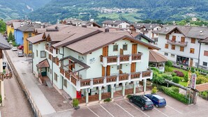 Ein Hotel mit Balkon, Parkplatz und Blick auf das umliegende Dorf.