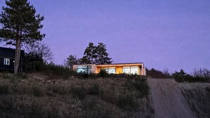 A modern house with large windows and a dirt road leading to it. - Beautiful home in Knebel with sauna (Knebel)