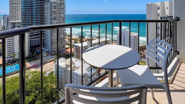 Balcón con mesa y sillas con vista a un paisaje urbano y al océano.