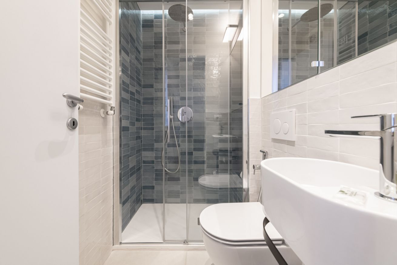 Un bagno moderno con doccia vetro, water bianco e un ampio lavandino bianco.