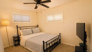 A bedroom with a bed, a ceiling fan, a TV, and a lamp. - Waterfront Escape w/ Private Pier • Minutes to BWI (Glen Burnie)