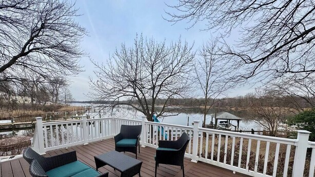 A wooden deck with outdoor furniture and a white railing overlooking a body of water. - Waterfront Escape w/ Private Pier  • Minutes to BWI (Glen Burnie)