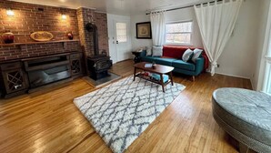 A living room with a fireplace, a sofa, a coffee table, and a rug. - Waterfront Escape w/ Private Pier • Minutes to BWI (Glen Burnie)