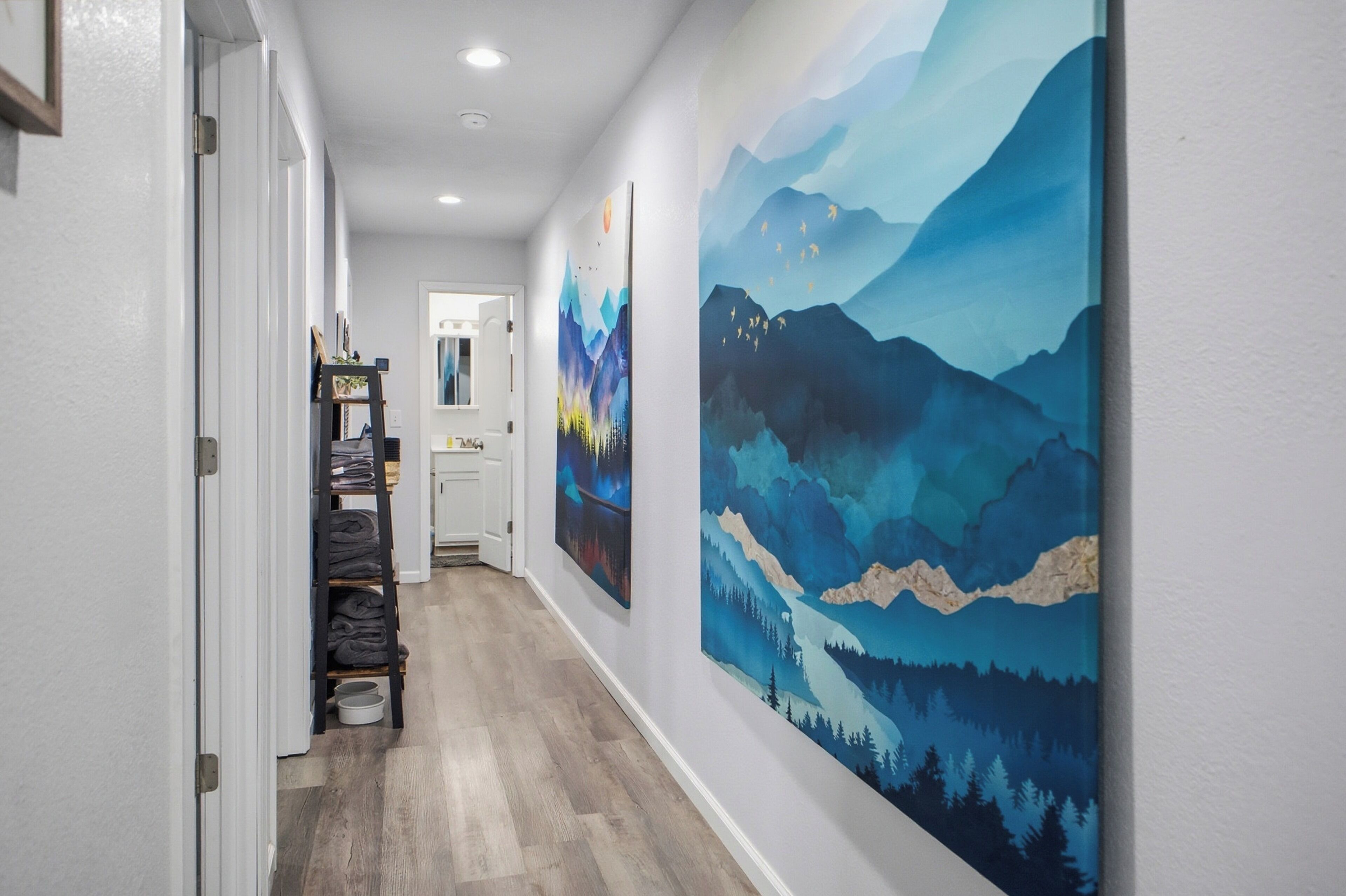 Bright, art-lined hallway with stocked linens and easy bath access.