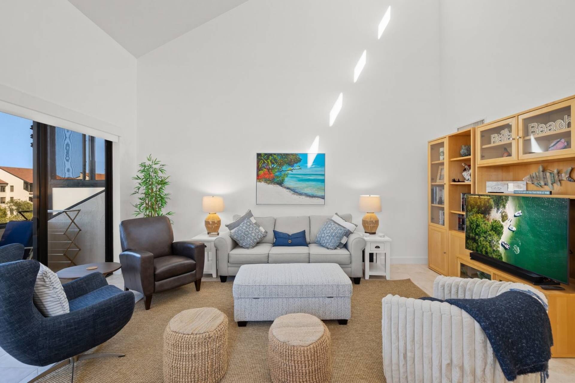 A modern living room with a sofa, armchairs, a coffee table, and a television.