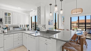 A modern kitchen with white cabinetry, granite countertops, and pendant lighting. - Excelsior: The Sky Loft (Siesta Key)