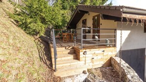 Una baita di legno con un balcone, un muro in pietra e una ringhiera in metallo.