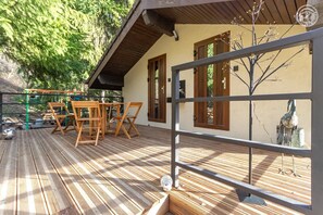 A wooden deck with outdoor furniture, a pergola, and a view of a bird in a window. - LE CROë - HAUTECOUR - Gîte (HAUTECOUR)
