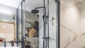 Un bagno moderno con cabina doccia in vetro, pavimento in marmo e mobile lavabo in legno.