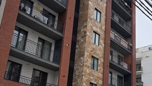 Un edifici residencial de diverses plantes amb balcons, terra coberta de neu i un cotxe aparcat.
