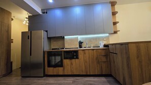 Eine moderne Küche mit Holzausstattung, einem Edelstahlkühlschrank und einer eingebauten Mikrowelle.