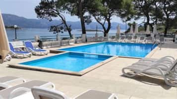 Una piscina al aire libre de temporada, sillones reclinables de piscina