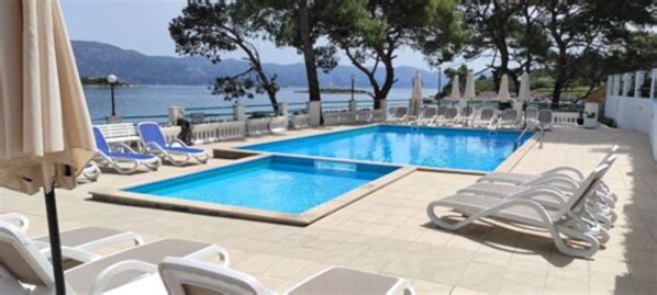 Una piscina al aire libre de temporada, sillones reclinables de piscina