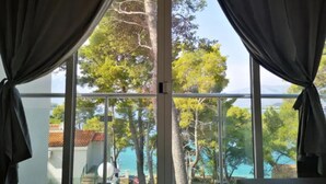 A room with large windows, curtains, and a view of trees and a body of water. - Lumbarda Resort Apartments (Lumbarda)