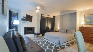 A bedroom with a bed, a sofa, a TV, a fireplace, and a mirror. - Quaint Studio Condo - 209 Lava Hot Springs Resort (Lava Hot Springs)