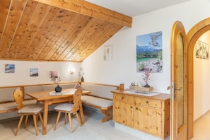 A wooden dining area with a bench, table, and chairs.