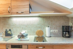 A modern kitchen with wooden cabinets, a built-in coffee machine, and a stone backsplash.