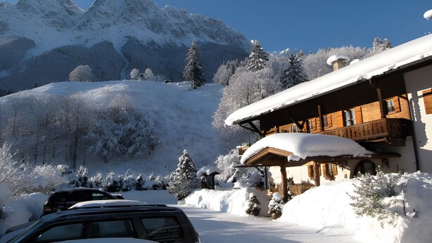 A snow-covered mountain landscape with a wooden building featuring a covered porch. - Apartment Kramer with Mountain View and Wi-Fi (Grainau)