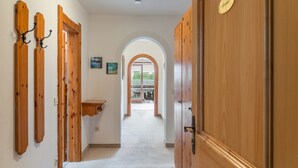 A hallway with wooden doors, a small shelf, and a view through an arched doorway to an outdoor area. - Apartment Kramer with Mountain View and Wi-Fi (Grainau)