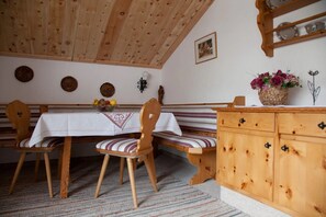 Ein Essbereich mit Holztisch, Stühlen, einer Bank und einem Holzschrank.