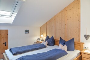 Ein Schlafzimmer mit einem hölzernen Kopfteil, einem Bett mit blauer Bettwäsche, einem Nachttisch mit Lampe und einem kleinen Gemälde an der Wand.