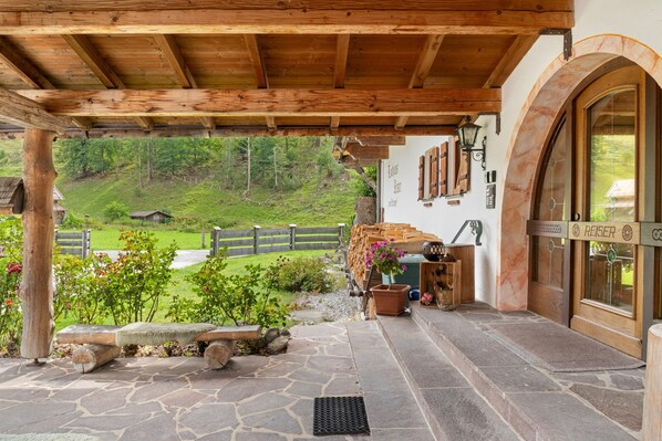 Eine hölzerne Veranda mit Steinböden, einem rustikalen Zaun und Blick auf einen grünen Hang.