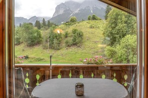 Une table avec une bougie dans une pièce d’où l’on peut admirer un paysage montagneux.