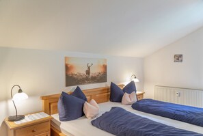 Un dormitorio con dos camas, una mesita de noche, una lámpara, un cuadro y un radiador.