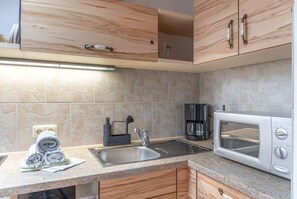 A modern kitchen with a granite countertop, stainless steel sink, and a built-in microwave. - Apartment 'Waxenstein' with Mountain View, Balcony and Wi-Fi (Grainau)