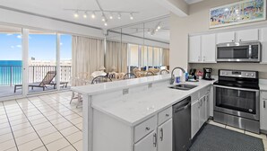 Una cocina moderna con una isla grande, electrodomésticos de acero inoxidable y vista al océano.