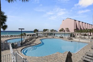 Ein Poolbereich mit Liegestühlen und Blick aufs Meer.