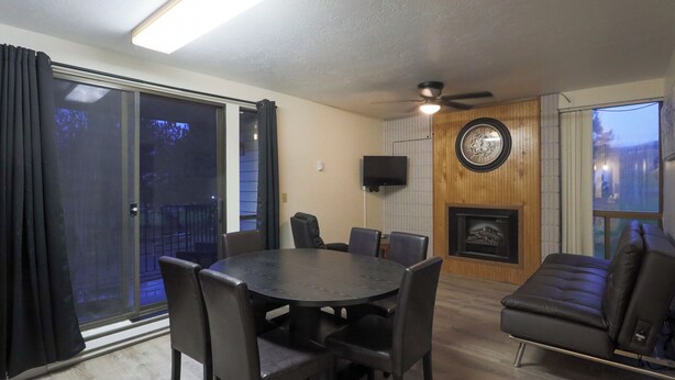 A room with a round table, chairs, a sofa, a fireplace, a TV, and a sliding glass door. - Quaint 1-bedroom condo - 112 Lava Hot Springs Resort Building A (Lava Hot Springs)