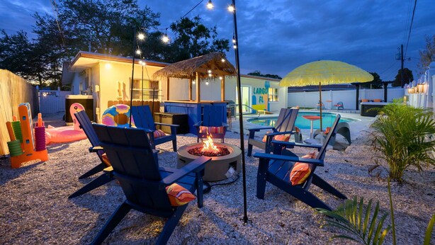 An outdoor patio area with lounge chairs, a fire pit, and a pool. - Backyard Oasis • Pool •  Hot Tub • Putt Putt • Bar (Largo)